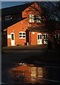 Stapleford Abbotts village hall reflected on a wet road in RM4 1EG
