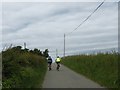 Cyclists climbing the hill towards Penmynydd farm in LL65 4YF