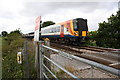 A train approaches the footpath crossing east of Wool Station in BH20 6BN
