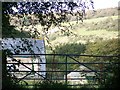 Mottistone Down and farm buildings seen through gate in PO30 4DP