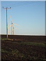 Electricity pole in field with wind farm behind in MK46 5JN
