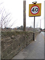 Stone wall alongside the A5119, and a bench mark in CH7 1UQ
