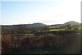 Over the road and the field towards the hill in SY6 7JX