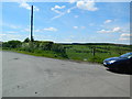 Road junction and pasture, near North Rhodes Plantation in FK1 2JX