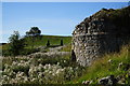 Side view of disused lime kiln looking towards derelict building in EH26 8QQ