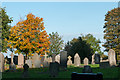 Gravestones with autumnal trees in DL16 7XJ