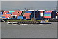 Tug "Progress" pushing barges past piled containers on Barking Reach in SE28 8FX