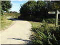 Farm road with signpost at footpath crossing in Coombes