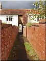 Footpath through archway between stone houses, Podington in Podington