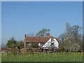 Newhouse Farm Cottage seen across a field in ME13 9QR
