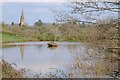The spire of Hallow church reflected in a pond in WR2 6PW