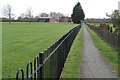Footpath into Cheddington with an orchard on the right in LU7 0RZ