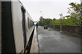 Diesel multiple unit number 156469 calls at a wet Millom Station in LA18 4AR