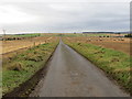 Minor road passing through arable land near Hindhillock in AB43 6QJ