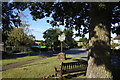 Seat and village sign opposite Little Yeldham church in Little Yeldham