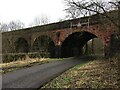 Minor road under disused railway viaduct in KA18 2QY