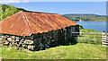 A charming rust-roofed barn near Kildonan, with Loch Greshornish in the distance in IV51 9PU