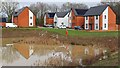 Houses seen across balancing pond beside Whiteley Way in PO15 7RR