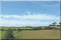View across farmland towards the churchyard of Ceirchiog Church in Bryngwran Community